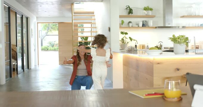 Mother entering arms open, daughter running from right, reuniting, hugging at table with juice