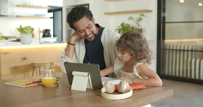 Father and child following tablet, pointing at tablet on stand at table for study