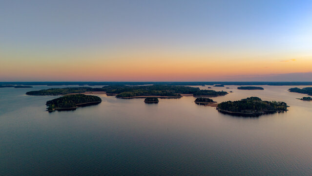 Top-down aerial view of small boats at a wooden pier on the rocky coast of Turku Archipelago