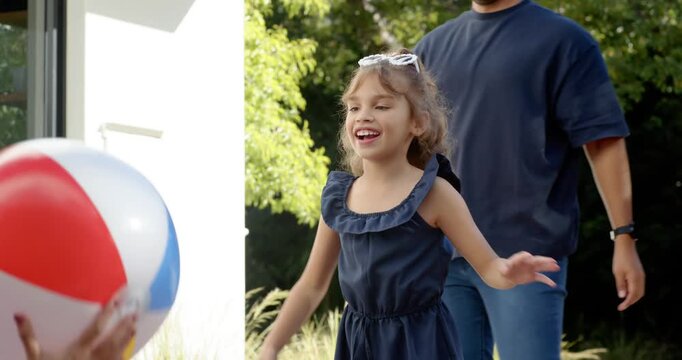 Family child reaching for colorful beach ball when adult handing left, man tossing on patio playing
