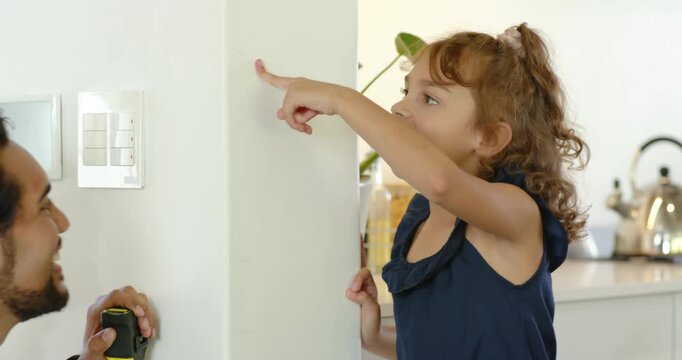 African American family seeing girl navy dress pointing at wall dad using tape measure marking spot