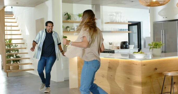 Couple dancing in modern kitchen with man entering from left, holding hands, twirling near island
