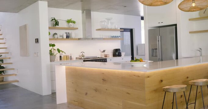 Camera is dollying left-to-right to show wooden island with LED lighting, centering fruit bowl