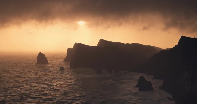 Dramatic golden sunset view of the volcanic rocky cliffs of Madeira island Portugal and stormy ocean at Ponta de Sao Lourenco coast