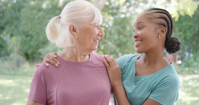 Diverse senior grandmother and granddaughter on porch, adult placing hand, laughing together