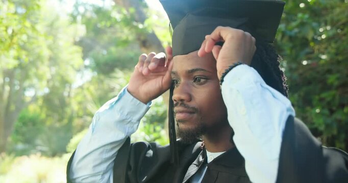 African American man checking fit adjusting cap fixing gown checking tassel in park, copy space