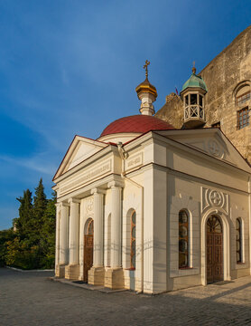 Orthodox Church of Panteleimon Healer of Inkerman Monastery, with its red roof and golden dome is on rocky. Above it, two bell towers with green roofs can be seen. Sevastopol, Crimea - October 9, 2014