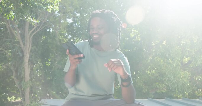 African American man seeing notification, chatting on smartphone and gesturing on white ledge