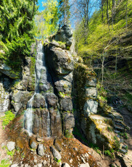 View of cascading waterfall over moss-covered rocks and cliffs, framed by lush forest, Polana, Banska Bystrica Region © TTstudio