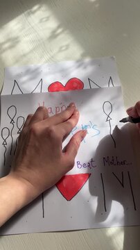 Vertical top-down video: on a white table a Mother&rsquo;s Day card is being created, drawing colorful balloons with markers in a simple festive style.
