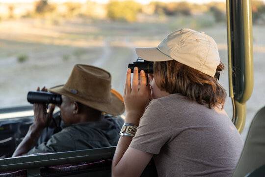 12 year old boy looking through binoculars, Okavango Delta, Botswana, Africa