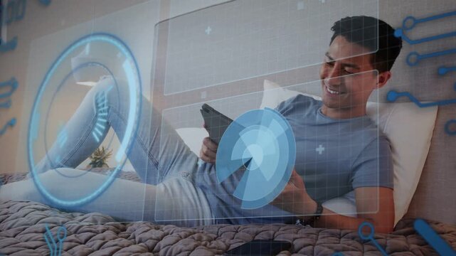 Adult man lying on bed tapping tablet activating blue tech HUD rotating circular UI using app