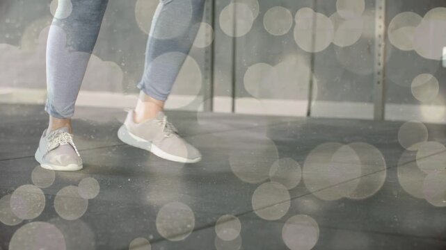 Woman doing lunges, step-throughs in gym, pushing front foot, bokeh highlighting shoes for strength