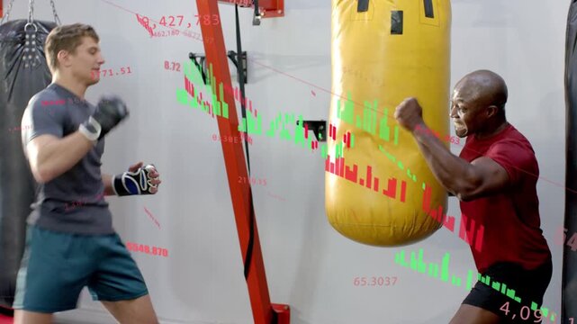 Trainee launching kick and punch in boxing training, trainer holding bag, finance charts scrolling