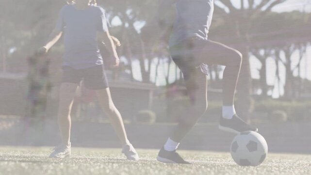 Defender pressing behind, attacker shielding and feinting to advance soccer ball on turf low camera