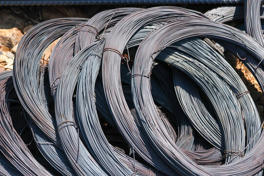 Heavy coil of steel wire sits ready on construction site, displaying strong and solid metallic presence. Raw iron material waiting for next big building project to begin with tough grace