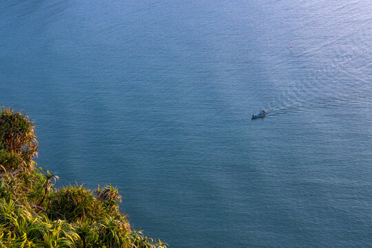 Peaceful calm blue sea water ocean landscape nature travel photography showing tiny distant boat sailing across vast surface providing tranquil solitary relaxing emotion