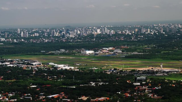 Aerial view of Asuncion, Paraguay showing city skyline, airport runway, and surrounding urban landscape. Shot from airplane window, highlighting infrastructure, travel, and South American city develop