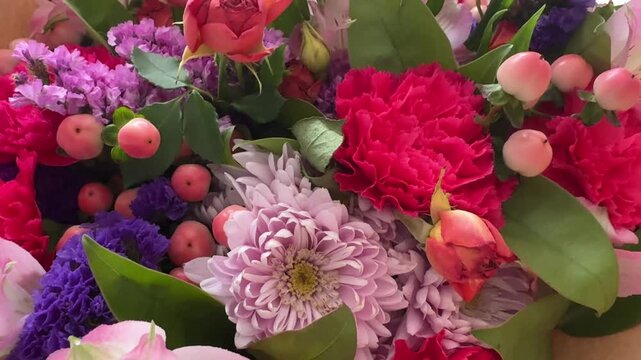 Camera moving over mixed bouquet revealing hot pink carnations chrysanthemum alstroemeria and statice. Floral 4K video with hypericum berries.