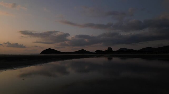 父母ヶ浜の夕暮れリフレクション ドローン空撮 香川・三豊市の絶景Drone aerial view of a stunning sunset reflection at Chichibugahama Beach in Mitoyo, Kagawa, Japan. The calm tidal flats create a mirror-like surface reflecting the col