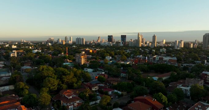 Aerial view of Asuncion at sunset showing residential neighborhoods, greenery, and modern skyline. Captures warm light and urban development in Paraguay&rsquo;s capital.