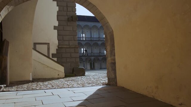 Handheld camera moving through stone gate into courtyard at Jindrichuv Hradec Castle Czech Republic with arcades