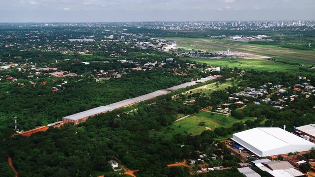 Aerial view of Asuncion, Paraguay featuring airport runway, suburban neighborhoods, and distant skyline. Ideal for travel, infrastructure, logistics, and urban development visuals in South America.