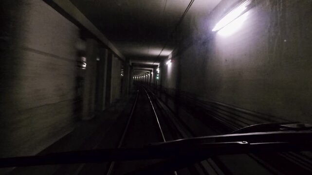 POV U-Bahn Fahrt durch beleuchteten Tunnel mit zwei Gleisen und Weiche