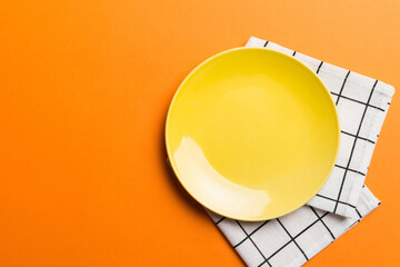 Naklejka premium Top view on colored background empty round yellow plate on tablecloth for food. Empty dish on napkin with space for your design