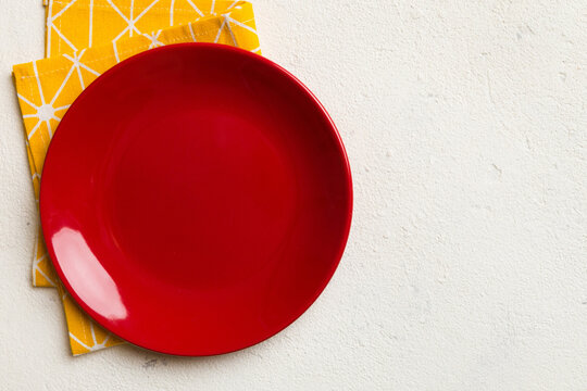 Top view on colored background empty round red plate on tablecloth for food. Empty dish on napkin with space for your design