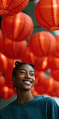 Fototapeta premium Young woman smiling beneath hanging red lanterns in hall