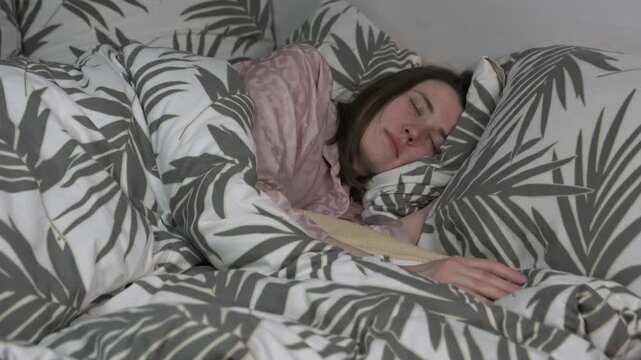 Young woman sleeping in bed with patterned sheets at home in the morning