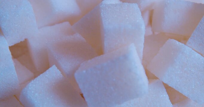 Close-up of white sugar cubes lying on a neutral surface bathed in soft, diffused morning sunlight. 
