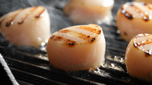 Fresh sea scallops searing on a hot outdoor charcoal grill.
