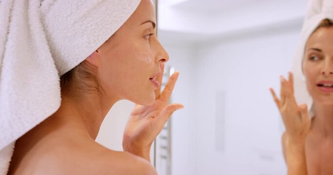 Cream, woman and skincare with mirror in home for self care, moisturiser and clear skin. Happy person, facial and reflection in bathroom with towel for hygiene, grooming and wellness with dermatology