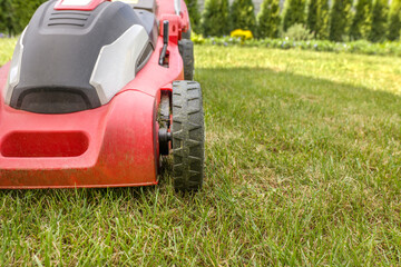 Obraz premium Lawn mower on a green meadow. Gardening equipment