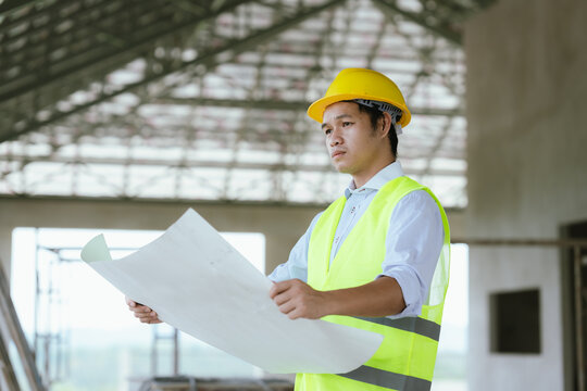 Engineer in safety gear reviewing blueprints at a construction site, representing architecture, project planning, site inspection, and modern construction management.