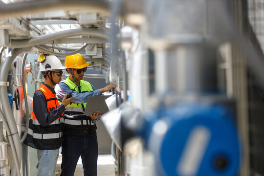 engineers inspecting industrial hvac system on rooftop. They check air cooling system and complex piping for routine maintenance and safety compliance