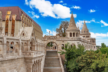 Naklejka premium The Fisherman's Bastion in Budapest features ornate stone towers and arched terraces under a bright blue sky.