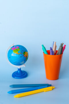 Global classroom studycore aesthetic with mini globe and dopamine stationery, colorful pens in orange cup on blue background, micro learning mood and edutainment school supplies in clean minimal style