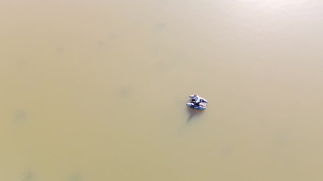 Aerial top down view of a fisherman in a sit-on-top kayak catching a fish in a calm lake