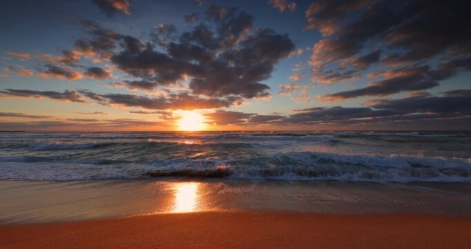 Golden sunrise over the ocean beach with crashing waves