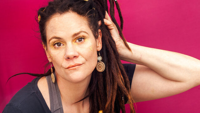 Confident Alternative Woman with Dreadlocks on Pink Background
