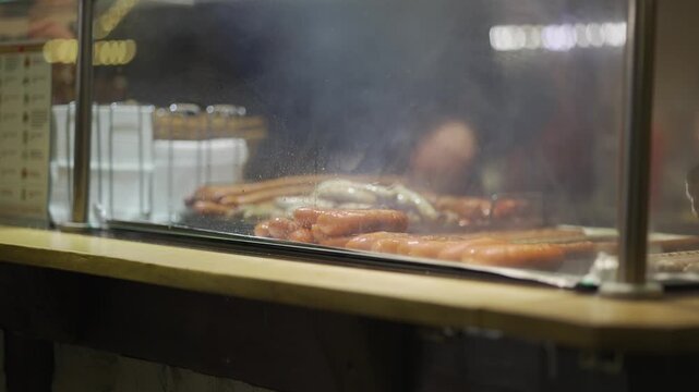Bavarian Christmas market food stall, freshly grilled sausages steaming behind glass counter. Fast street food, warm winter snacks, traditional German flavors attract visitors in festive atmosphere
