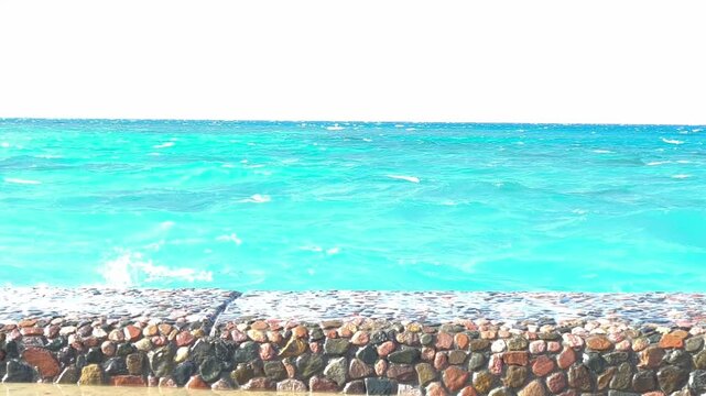 Straw beach umbrella and turquoise ocean waves. Peaceful view from under a straw beach umbrella looking out at the calm turquoise sea with gentle waves washing ashore on a beautiful sunny day.