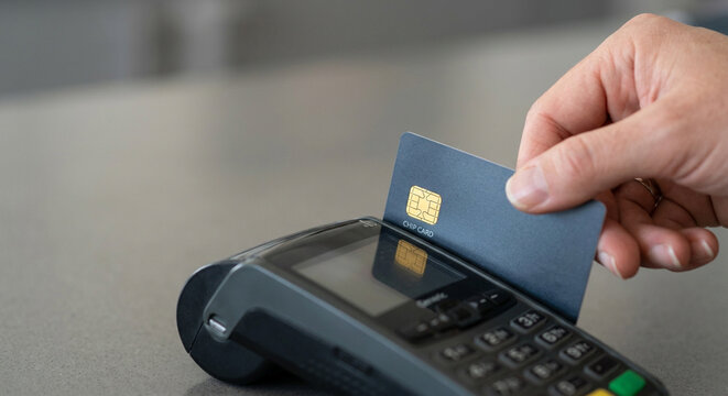 Hand inserting a chip card into a credit card reader terminal for a secure retail transaction at a store checkout.
