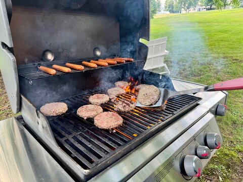 Man flipping hamburger patties on a grill on the Fourth of July in New Jersey