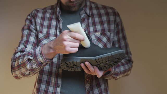 A person performs leather boot maintenance by applying cream to the toe area. The closeup shows cleaning, protection and long term care.