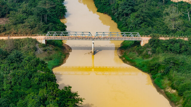 Illegal galamsey gold mining in ghana, polluted brown river passing under a bridge