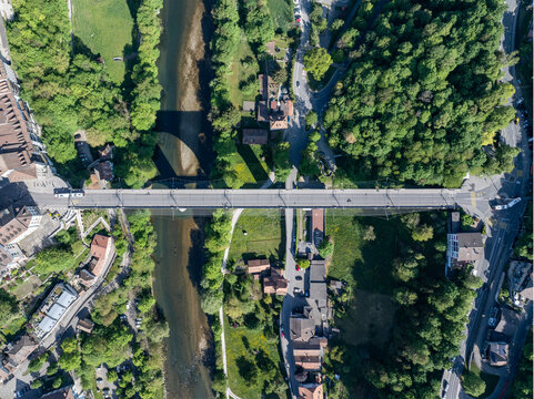 Aerial view of Pont de Zaehringen spanning the Sarine river surrounded by lush green trees and urban buildings in Fribourg, Fribourg, Switzerland.